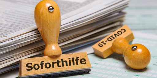 Zwei Stempel die auf Unterlagen liegen, auf dem einen steht Soforthilfe und auf dem anderen Covid-19